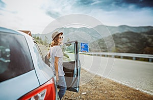 Travel - young beautiful hipster woman in hat travel by car, rent a car in vacations, image with retro tone