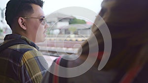 Traveler Asian backpack couple sitting on bench while waiting train, Young sweet couple tourist backpacker enjoy their journey in