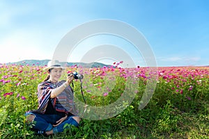Traveler Asian women sitting and take a photo in the flower field and hand touch cosmos flower, freedom and relax in the flower me