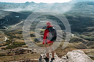 A traveler on the background of mountains. A tourist stands on top of a mountain. Male traveller in the mountains, rear view.
