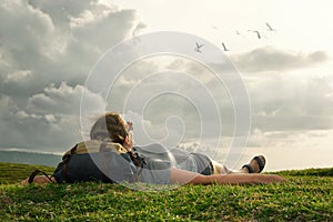 Traveler with backpack looking at sky and clouds over mountains