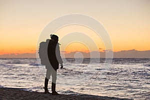 A traveler with a backpack is standing on the shore of Japanese Sea