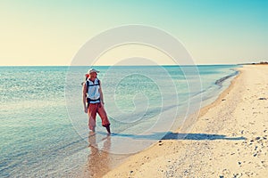 Traveler with backpack stands on the deserted beach