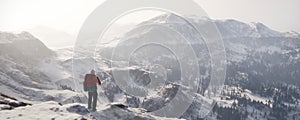 Traveler with a backpack on top of snow mountains