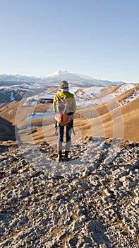 Traveler with a backpack. The view from the back. In the background, the beautiful mount Elbrus. Single independent trip around