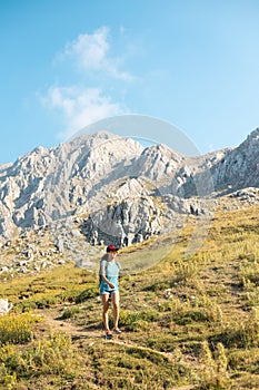 a traveler with a backpack walks along a mountain path. a girl walks in the mountains