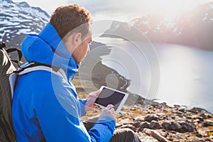 Traveler backpacker using digital tablet computer outside in mountains