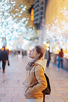 Traveler with bag visiting Roppongi Hills Christmas Illumination during winter season, happy tourist woman stands on a christmas