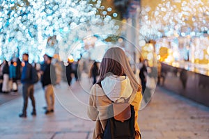 Traveler with bag visiting Roppongi Hills Christmas Illumination during winter season, happy tourist woman stands on a christmas