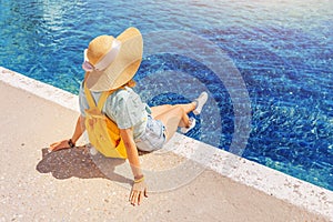 traveler in a big hat resting and relaxing on the pier near the beautiful sea of blue. Minimalistic composition