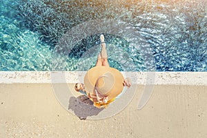 Traveler in a big hat resting and relaxing on the pier near the beautiful sea of blue. Minimalistic composition