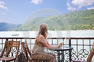 Traveler blogger girl sitting in a cafe and looking at a beautiful mountain lake