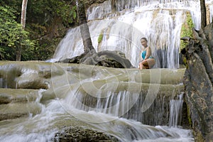 Traveler with blue swimsuit happy at Erawan Waterfall and natural