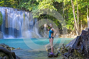 Traveler in blue swimsuit stand relax at Erawan Waterfall and natural