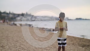 Cestovatel chlapec chůze na pláž chytrý telefon v chatování napsat. přenosný ruční zařízení 