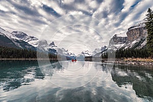 Traveler canoeing on Maligne lake with altocumulus clouds in Jasper