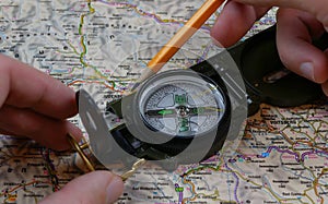 Traveler charting a course with map and compass. Compass used for measuring distance on atlas map
