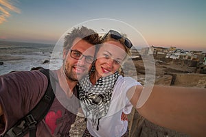 Traveler couple taking selfie on city fortress wall of Essaouira, Morocco.