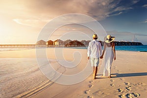 A traveler couple walks along a tropical beach in the Maldives