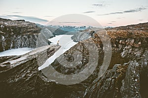 Traveler on the edge of Trolltunga cliff traveling in Norway