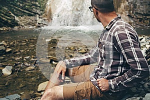 Traveler Explorer Sitting And Looks On Waterfall. Travel Hiking Destination Experience Lifestyle Concept