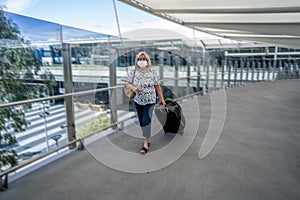 Traveler with face mask affected by coronavirus travel ban and COVID-19 pandemic flight restrictions