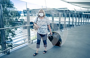 Traveler with face mask affected by coronavirus travel ban and COVID-19 pandemic flight restrictions