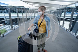 Traveler with face mask affected by coronavirus travel ban and COVID-19 pandemic flight restrictions