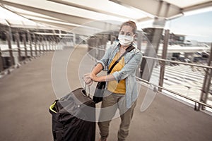 Traveler with face mask affected by coronavirus travel ban and COVID-19 pandemic flight restrictions