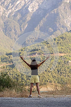 Traveler female in summer outfit standing with her hands raised