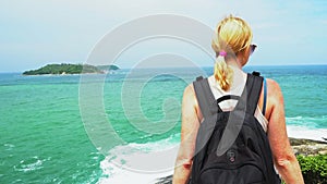 Traveler girl with a backpack standing on the beach and looking into the distance. beautiful seascape with rocks and sea