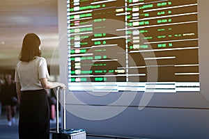 a traveler girl checking flight on the monitor in airport