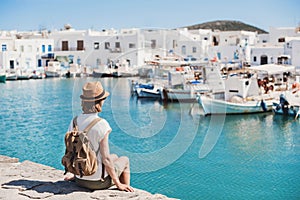 Traveler girl enjoying vacation in Greece. Young woman wearing hat looking at greek village with sea. Summer holidays, vacations,