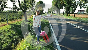 Traveler Girl hitchhiking on a sunny road and walking.