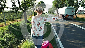 Traveler Girl hitchhiking on a sunny road and walking.