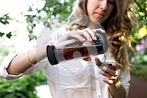 Traveler girl pouring tea in thermos cup, outdoors. Young woman drinking tea at cup. Theme travel. Woman pouring a hot drink in mu