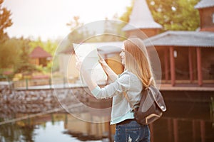 Traveler girl searching right direction on map, orange sunset light, traveling along Europe