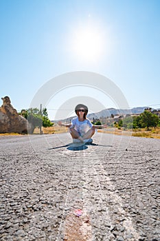 Traveler girl sitting on the road, tourist posing. Fairy chimneys park in the background. rock formations. Vertical photo. Travel