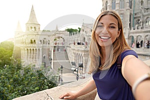 Traveler girl taking selfie on sunset in Budapest, Hungary. Young tourist woman takes self portrait on Fisherman`s Bastion in the