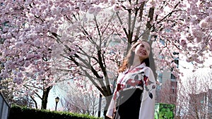 Traveler girl walk beautiful young Oriental girl waving her head developing her hair against the background of cherry