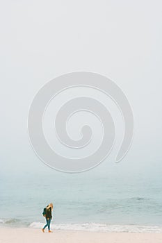 Traveler girl walking alone on foggy beach