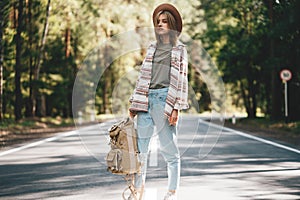 Traveler girl walking along the road to forest