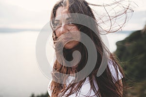 Traveler girl with windy hair relaxing on top of rock mountain, enjoying beautiful sunset view on river. Atmospheric moment. Copy