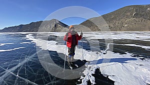 A traveler guy stands on skates on the ice of frozen Lake Baikal