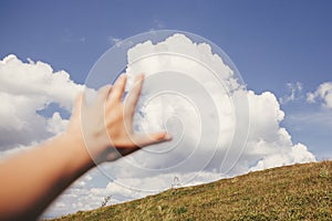 Traveler hand reaching out to mountains and sky clouds. focus on