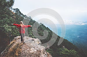 Traveler hands raised standing on mountains cliff