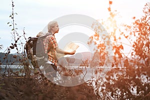 traveler hiker man with backpack hiking near lake. tourist backpacker with map relaxing in forest. travel lifestyle, summer