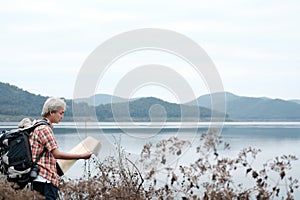 traveler hiker man with backpack hiking near lake. tourist backpacker with map relaxing in forest. travel lifestyle, summer