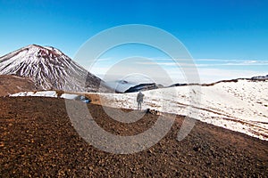 Traveler, hiker and tramper walking from Red Crater to South Crater, Mount Ngauruhoe an active stratovolcano in front of him