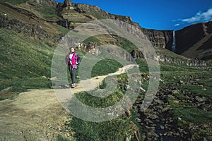 Traveler hiking at Hengifoss Waterfall, Iceland.